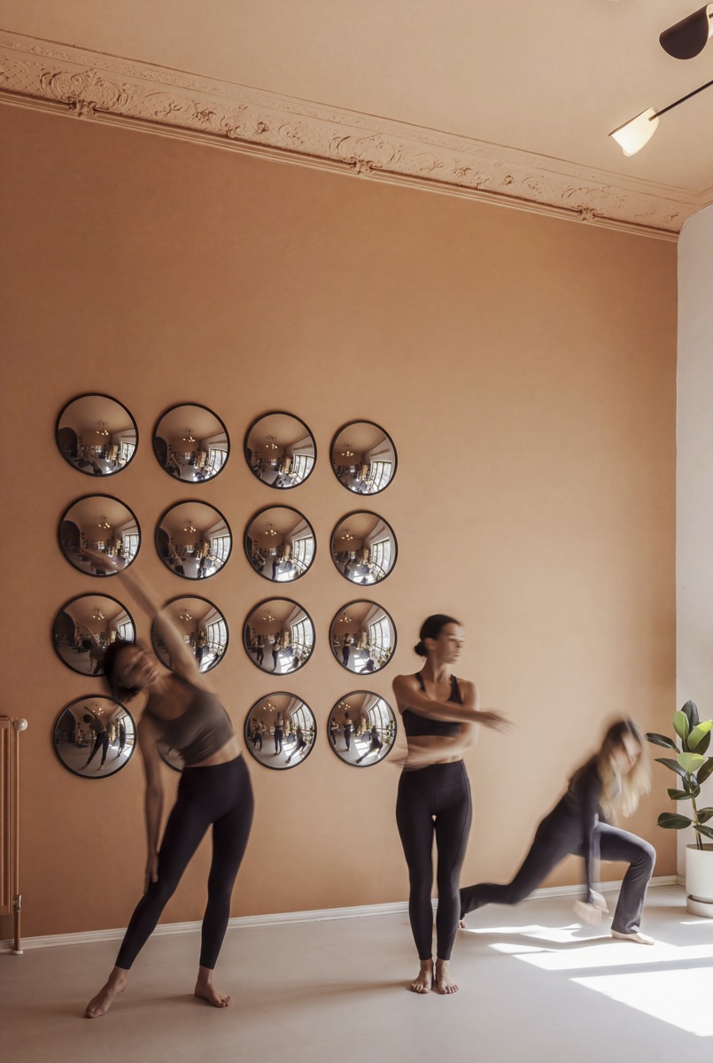 A small group moving upright in front of the mirror wall